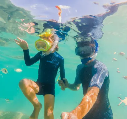A man and a child gaze at a shark in an aquarium, sharing a moment of wonder at the underwater world.